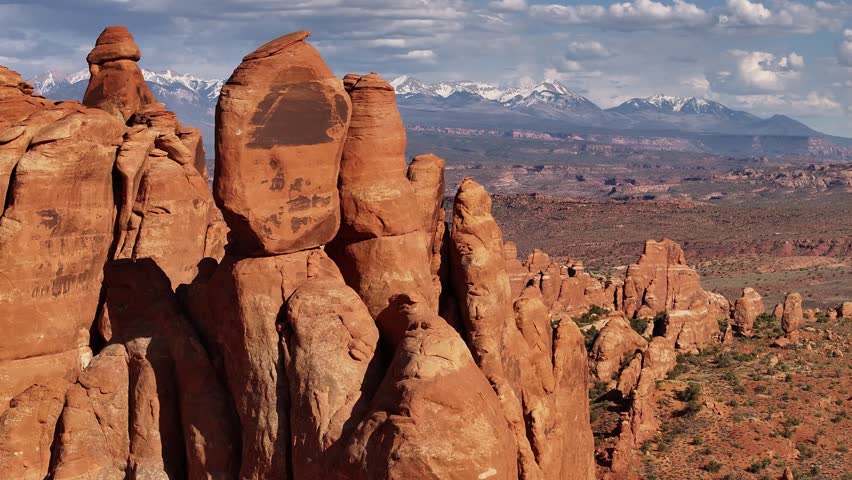 Aerial americana view of red rock formations with snow capped mountains backdrop, Moab Utah