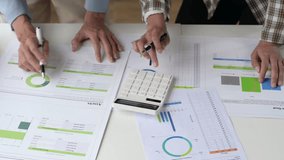 Business professionals collaborating, analyzing financial documents and charts, performing calculations on a meeting table - Powered by Shutterstock - Get 15% off with code: PIKWIZARD15