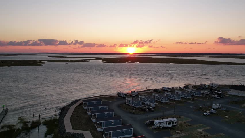 Aerial hyperlapse over campsite hotels on beach shores of Chincoteague Virginia as sun sets below horizon
