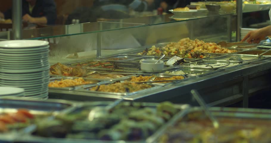 foods fron window of a restaurant lots of foods and a cook using spoon