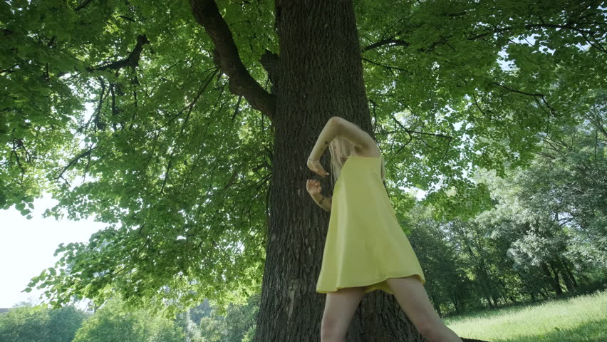 Happy beautiful young girl dancing of freedom in summer park with trees in the background.