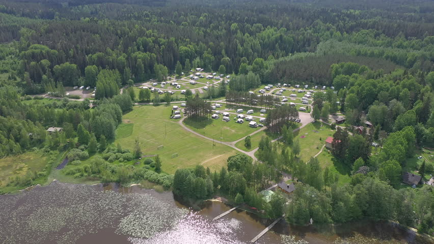 Beautiful drone shot of a trailer park next to a lake. Awesome caravan lifestyle and a perfect holiday opportunity. Aerial geology shot with the camera slowly moving forward and tilting downwards..