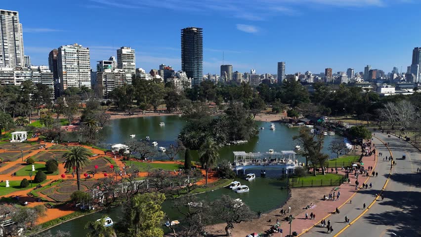 WS TS Lake with boats in the Rosedal Park in Buenos Aires with people walking and buildings in the background. Aerial tracking shot