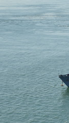 Vertical aerial view of a Navy battleship traveling on the open ocean. Identifiable hull markings removed for general usage.	