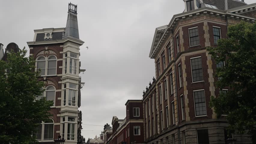 Traditional Dutch Historic Buildings By The Canal In Amsterdam, Holland, Netherlands. Low Angle Shot