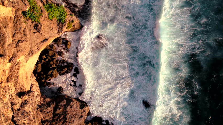 Top down video of waves crashing in ocean near Uluwatu temple in Bali Indonesia