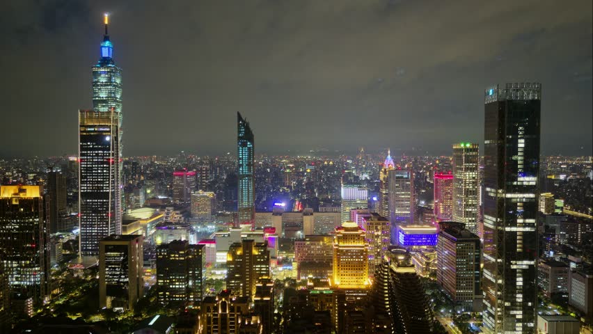 Aerial hyperlapse at night above Downtown Taipei, the vibrant capital of Taiwan, with 101 Tower standing out amid skyscrapers in XinYi Commercial District and city lights dazzling in the dark