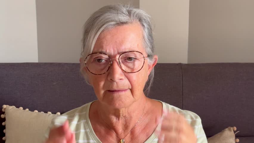 Concerned nervous senior mature woman feeling stress, sitting on couch, holding head, suffering from headache, emotional crisis, depression, anxiety, going through loss, mental disease, disorder