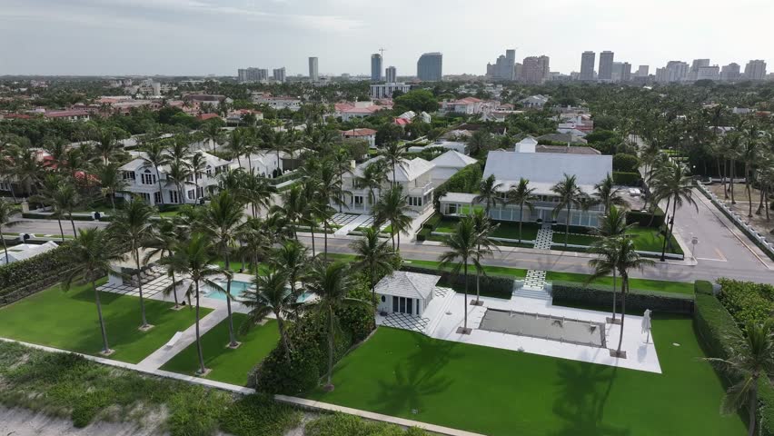 Exclusive housing area with modern villas in Suburb of West Palm Beach City. Sunset time with skyline in backdrop. Aerial forward flight. Exotic Palm trees on street of Florida.