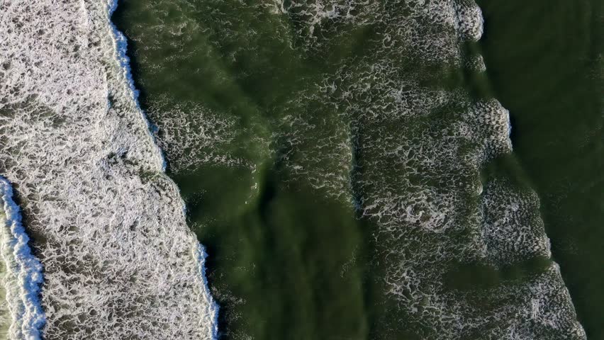Scenic aerial forward shot looking down at waves in the Pacific Ocean at Ocean Shores, Washington State
