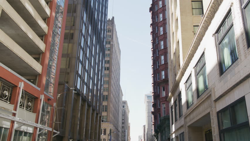 Slow-motion shot looking down the street in downtown St, Louis with large buildings lining both sides.