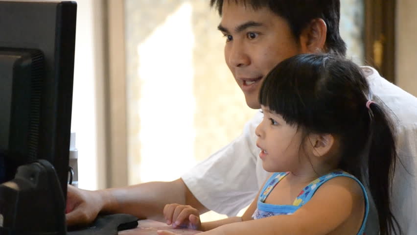 asian father teach cute daughter how to use computer