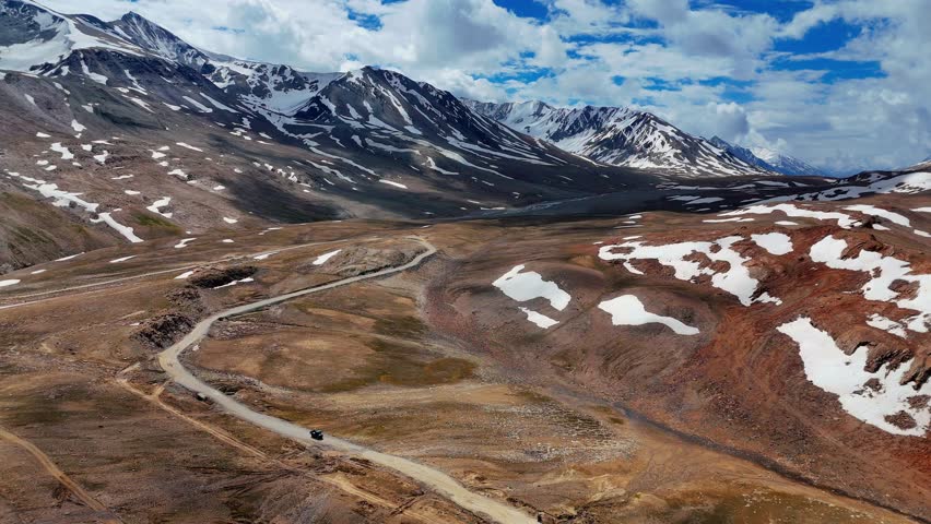 Scenic view of snow covered Himalaya mountains and clouds in sky as seen from Baralacha La pass in Himachal Pradesh, India. High altitude mountain pass. Scenic nature views.