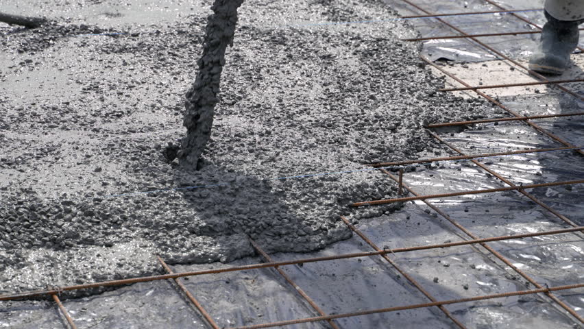 Pouring concrete through a pump onto a slab with a reinforced iron grid. Close-up of construction works.