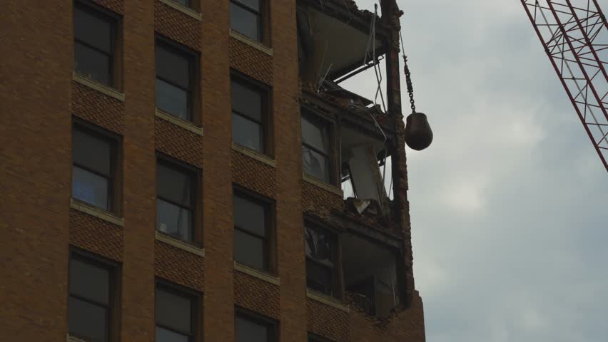 A dramatic moment captured during the demolition of a high-rise building in Youngstown, Ohio, as a wrecking ball makes contact, causing debris to fall from the structure.