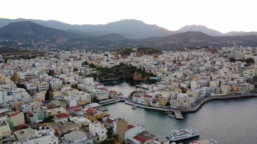 Approaching Aerial Panoramic View of Agios Nikolaos Coastal City and Voulisméni Lake, Crete, Greece