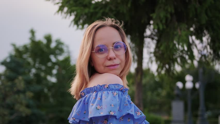 A Woman Stands Confidently in a Blue Off-Shoulder Top Surrounded by Lush Greenery During Golden Hour
