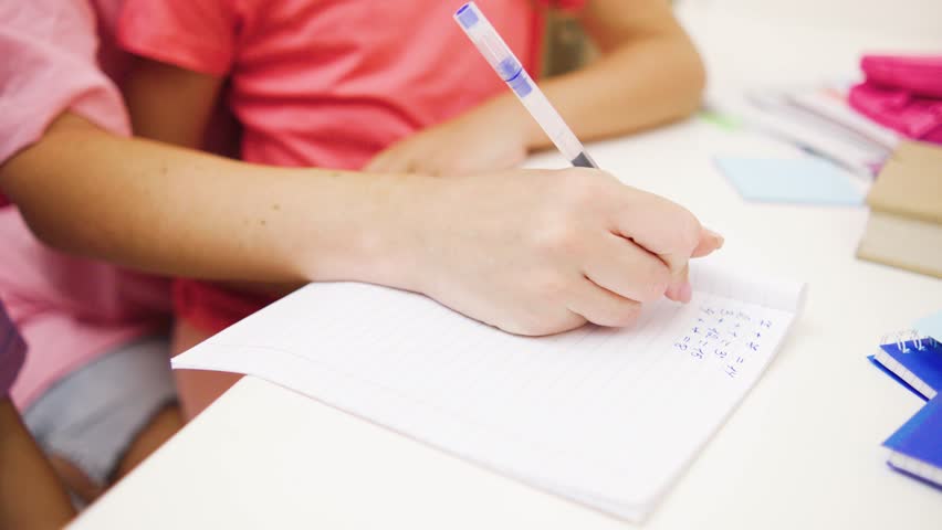 Close up shot of dedicated student writes intently on paper during a collaborative interactive learning session held in a bright and inviting classroom setting