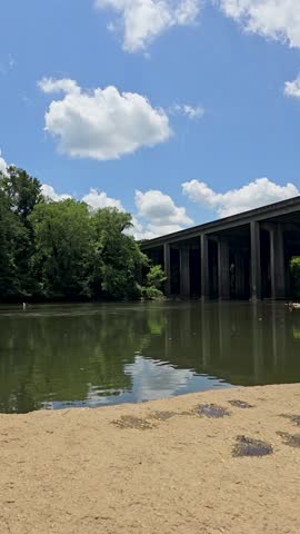 an African American man walking along the Chattahoochee River wearing a backpack with flowing water and lush green trees at Paces Mill in Atlanta Georgia USA
