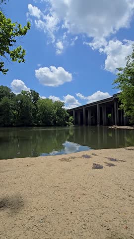 an African American man walking along the Chattahoochee River wearing a backpack with flowing water and lush green trees at Paces Mill in Atlanta Georgia USA