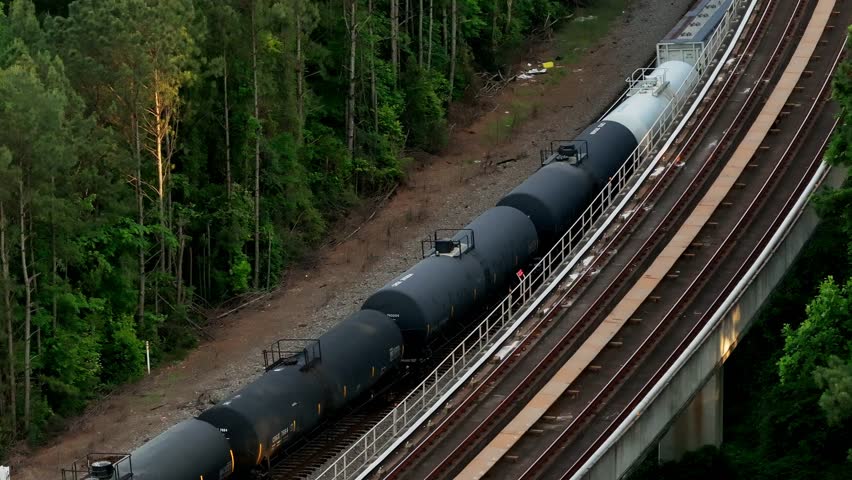 Aerial view of railway freight train crossing through natural forest trails