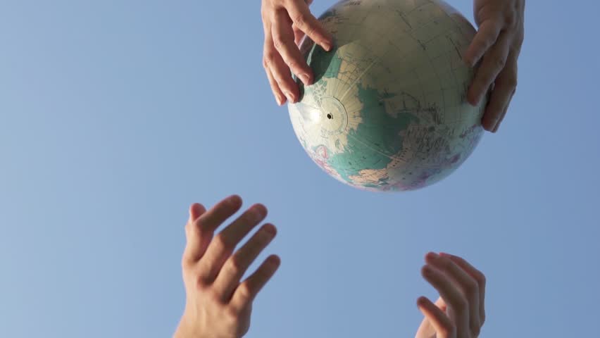 A child and his father throw a globe up. The future of the planet is in the hands of youth.