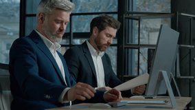 Two Caucasian men professional businessmen work together using computer in office discussing business project check financial data plan colleagues talking about marketing strategy corporate teamwork - Powered by Shutterstock - Get 15% off with code: PIKWIZARD15