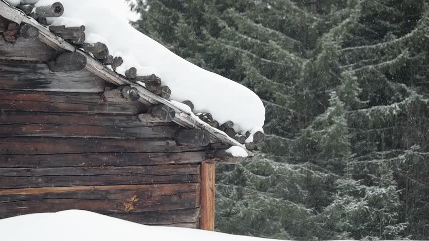 Winter cabin roof covered in snow in a rustic forest