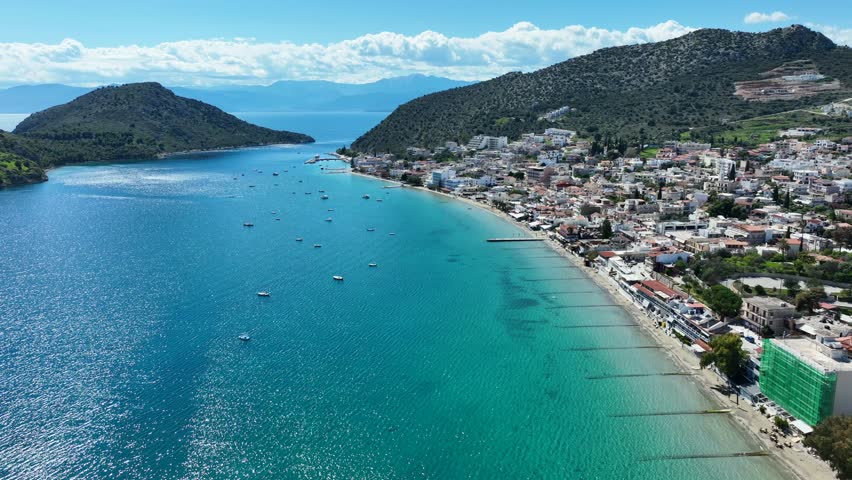 Aerial drone video of famous seaside village small port and long sandy beach of Tolo with hotels and resorts built by the sea, Argolida, Peloponnese, Greece
