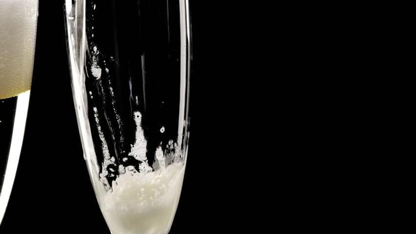 zoom out of two champagne glasses with sparkling firework explosion during the touch of the flutes, closeup of fizzy drink with golden firecrackers isolated on black background