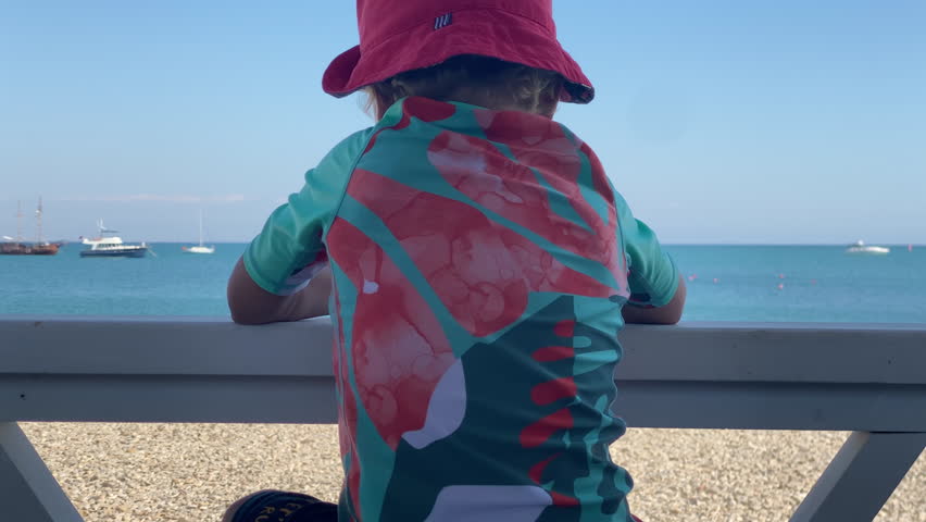 Little boy looking at beach and sea on summer day. Happy child on Tereshkova embankment. Yevpatoria, Crimea, Russia 2024
