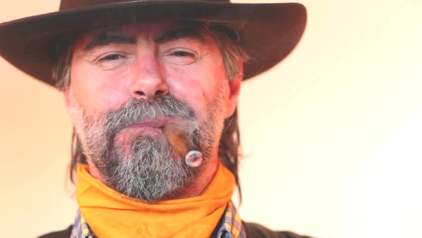 Closeup portrait of cowboy smoking cigar and laughing. on white background 