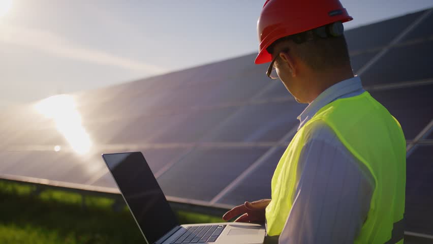 Engineer working use laptop stand near solar batteries construction renewable power worker man technology modern electricity energy slow motion