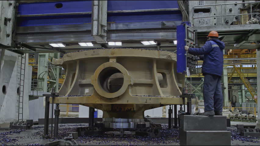 Worker with remote control and rotating lathe. Stock clip. Worker with control panel for factory metalworking machines. Turning carousel machine for metalworking