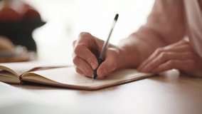Camera view of woman's hand holding pen and writing on diary. Female sitting at desk in home or office. Making marks in notepad. Noting shopping list or creating household tasks on paper. - Powered by Shutterstock - Get 15% off with code: PIKWIZARD15