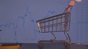 Modern economics. Business concept of securities trading. A small shopping cart from a supermarket stands against the background of a computer monitor on which economic data is changing. Close-up.
 - Powered by Shutterstock - Get 15% off with code: PIKWIZARD15