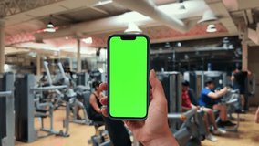 Girl hand holding a smartphone with empty green screen chromakey at the gym. - Powered by Shutterstock - Get 15% off with code: PIKWIZARD15