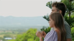 Young couple enjoying morning coffee on scenic balcony overlooking green hills and distant mountains. Outdoor leisure activity. - Powered by Shutterstock - Get 15% off with code: PIKWIZARD15