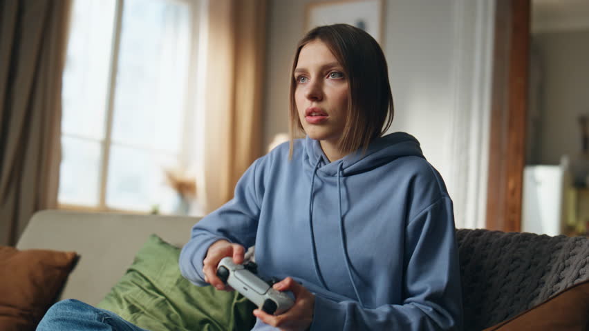Teenager playing video game failing online competition on apartment sofa closeup. Emotional woman throwing wireless console feeling despair about losing. Nervous female gamer disappointed videogame.