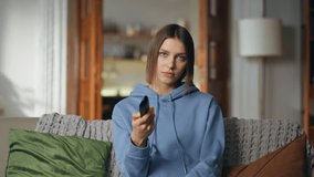 Bored woman watching TV at home couch closeup. Smiling girl switching channels by remote controller find favorite television show. Relaxed lady enjoy domestic weekend with interesting serial on sofa. - Powered by Shutterstock - Get 15% off with code: PIKWIZARD15
