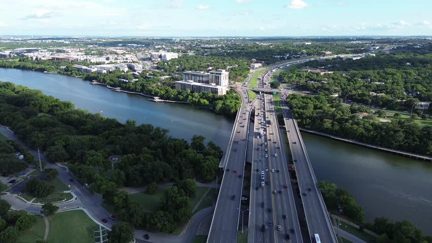 Heavy traffic over river highway Interstate 35 from Central Austin toward South Riverside neighborhood community, semi-trucks, cars travelling North South frontage road Colorado River boardwalk. USA 