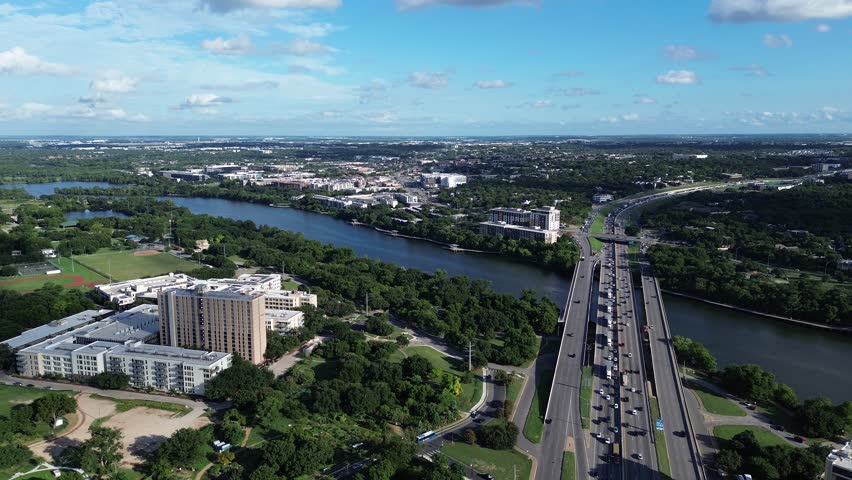 Flyover lush green trees Chicano Park near Interstate Highway 35 busy heavy traffic toward Riverside, Roy Ann Butler trail South of Austin, Texas, Colorado River boardwalk sunny cloud blue sky. USA