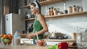 Cooking woman listen music in wireless headphones closeup. Smiling girl pouring milk into cereal bowl at modern kitchen. Happy lady dancing in earphones preparing healthy breakfast at cozy cuisine.  - Powered by Shutterstock - Get 15% off with code: PIKWIZARD15