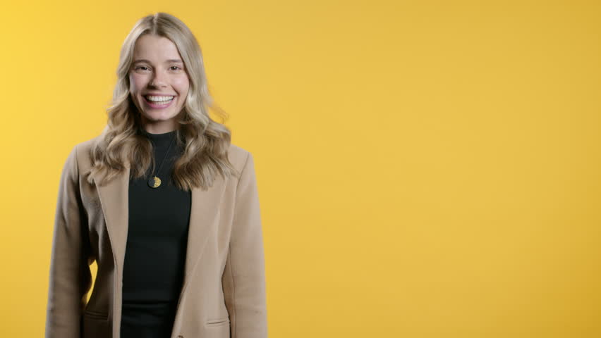 Smiling 30s aged student lady looking to empty place for your advertising. Recommending woman pointing at right side, copy space. Female presenting something isolated yellow background.High quality 4k