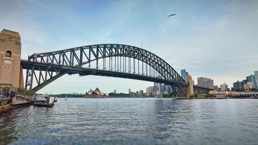 A time-lapse of ferries and boats crossing underneath the Sydney Harbor Bridge.