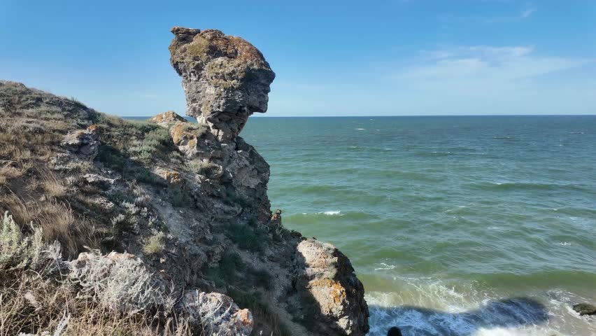 A stunning natural rock formation stands at the edge of the Sea of Azov, resembling a human head amidst vibrant coastal scenery in Crimea.