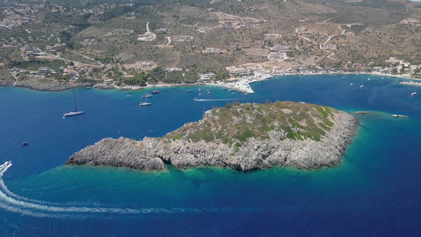 The drone aerial footage of Agios Nikolaos island, Agios Nikolaos Harbour and beach, Zakynthos, Greece.