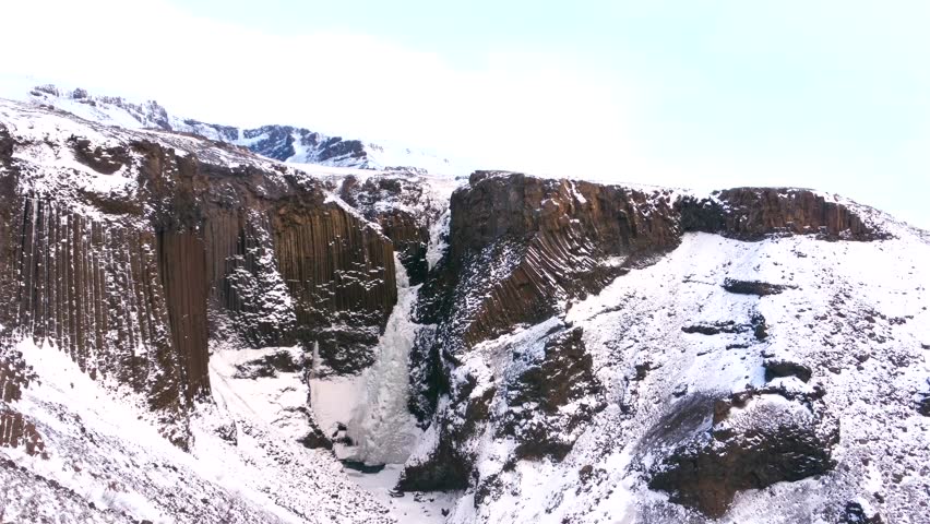 Hengifoss waterfall frozen in the cold Icelandic winter, detail of the volcanic cliffs