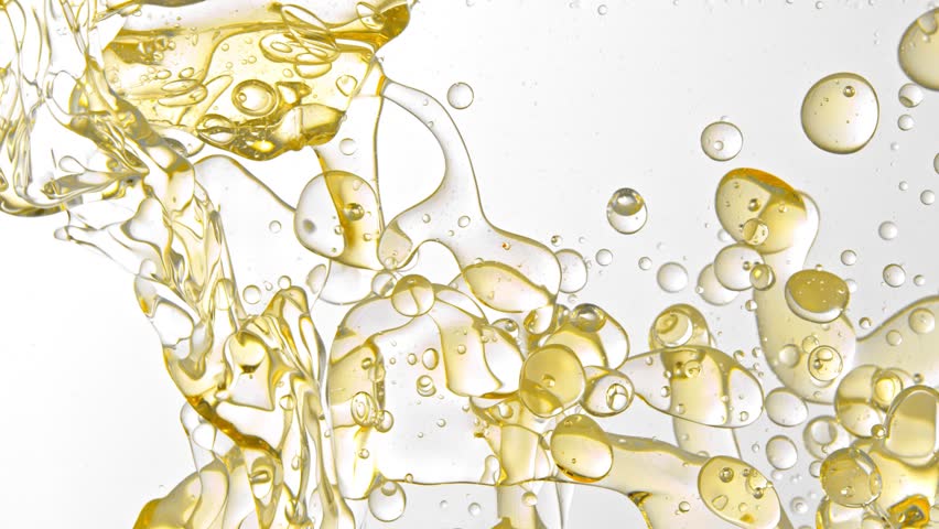 Super Slow Motion Shot of Golden Oil Flowing in Water on White Background at 1000fps.