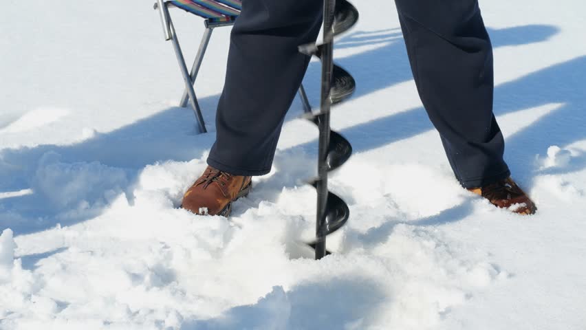 Ice fishing preparation: drilling hole with an auger